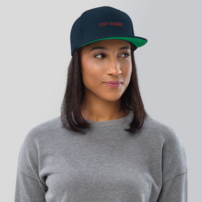Woman wearing a dark navy snapback with green under brim, that says top gamer